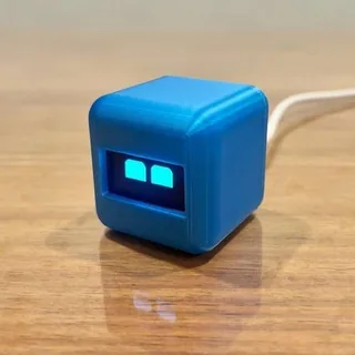 Small blue cube robot with glowing eyes on a wooden table